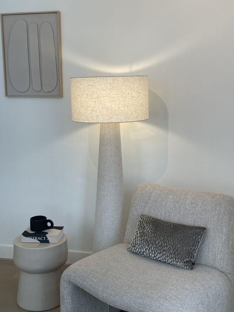 Detailfoto van een zandkleurige fauteuil met bijzettafel en staande lamp, stijlvol gestyled voor verkoop door The Staging Club in Zwolle.