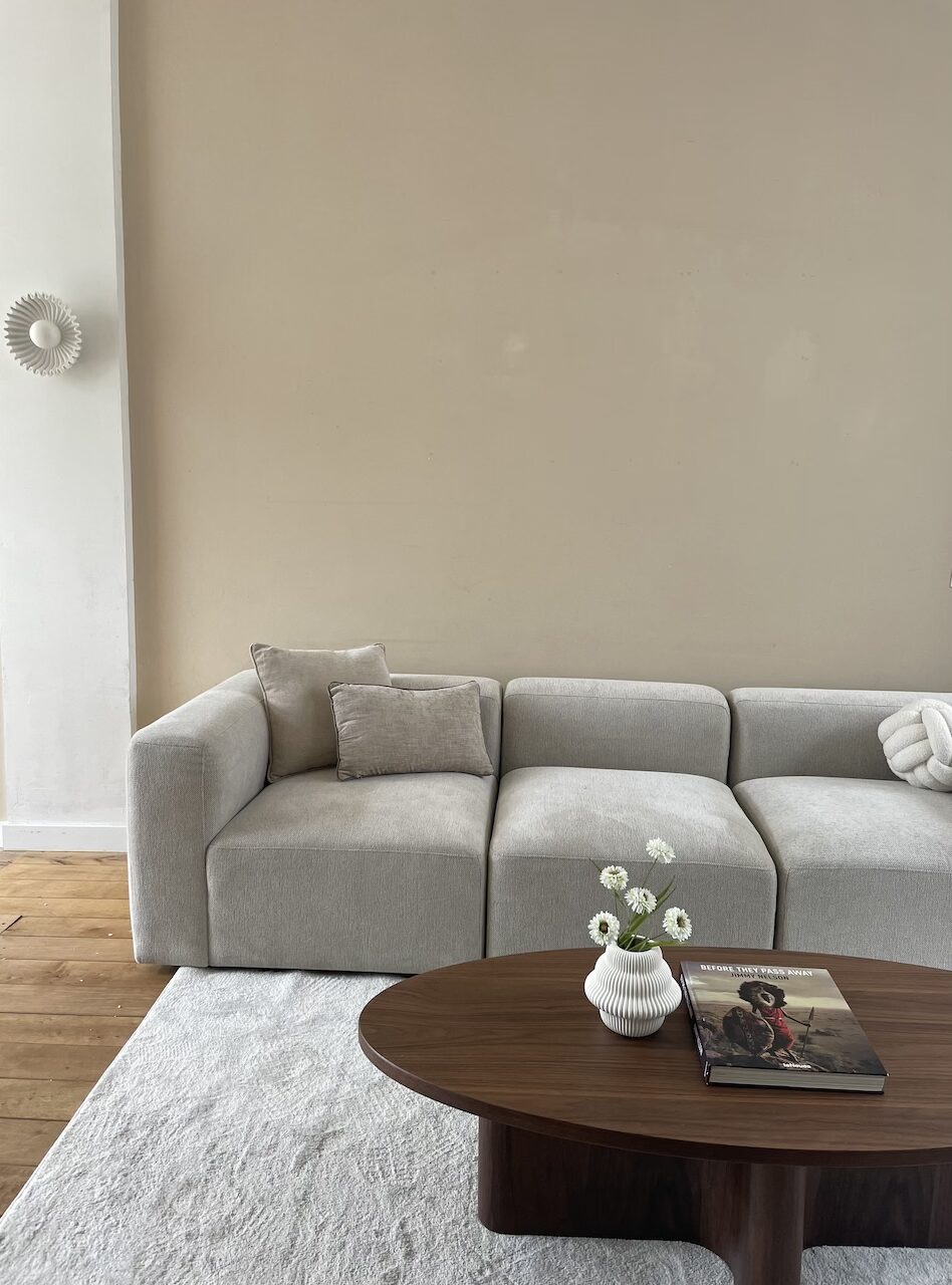 Verkoopstyling woonkamer met grijze bank en warme natuurlijke tinten