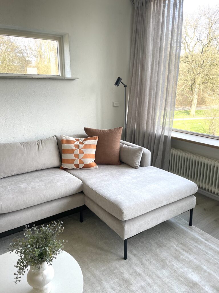 Woningstyling woonkamer met grijze bank en warme accessoires